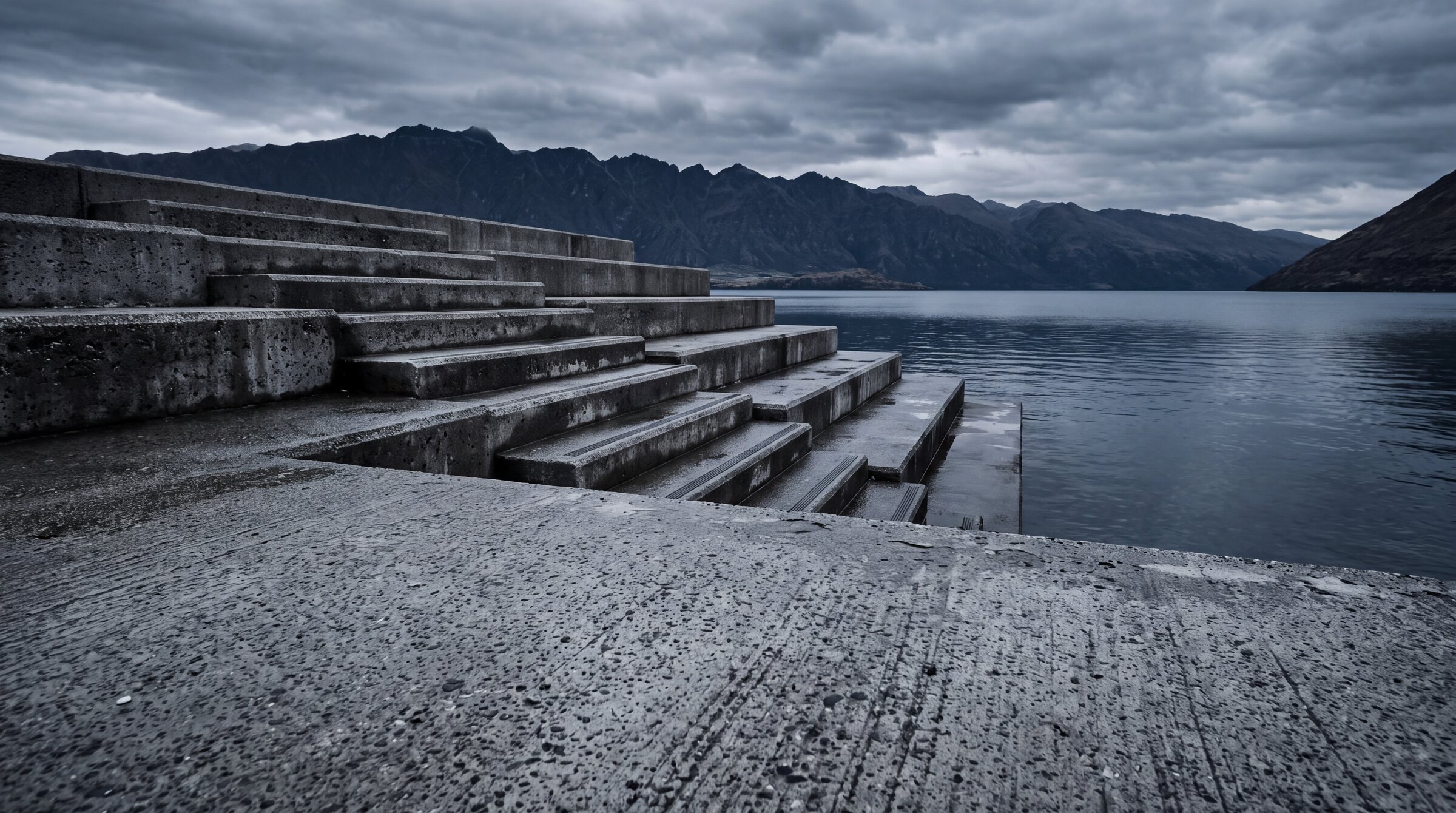 Wide exterior view of textured concrete steps and plaza meeting the lake edge